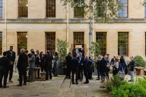 Delegates in conversation in an Oxford college courtyard.